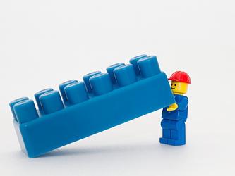 mini Lego workman pulls a blue Lego block